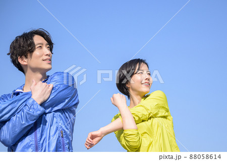 メインビジュアルにも!青い空で準備運動する健康的な男女 横顔 メインビジュアルにも!青い空で準備運動する健康的な男女 横顔 88058614