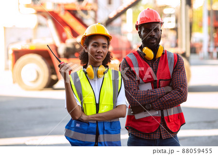 Serious two African american male and female worker checking control loading freight containers from Cargo freight ship for import export. Serious two African american male and female worker checking control loading freight containers from Cargo freight ship for import export. 88059455