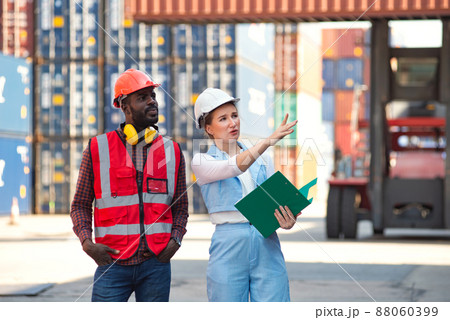 Businesswoman and engineer talking and checking loading Containers box from Cargo freight ship for import export. shipping in docks. Businesswoman and engineer talking and checking loading Containers box from Cargo freight ship for import export. shipping in docks. 88060399