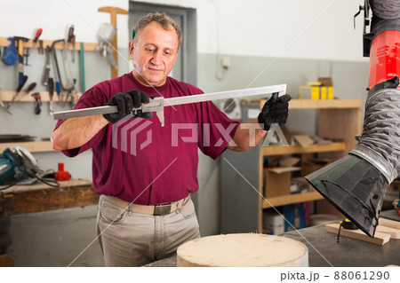 Worker performs measurements on wooden workpiece with caliper. Working with the measuring tool 88061290