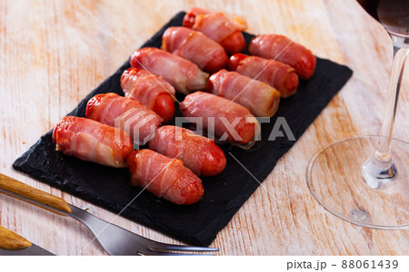 Rolled bacon with sausages on black dish 88061439