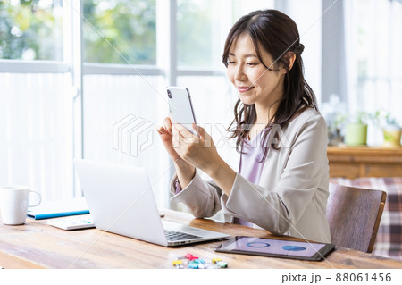デスクワーク中にスマホを操作するビジネスウーマン 88061456