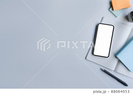 Mockup smart phone with blank screen, notebook and sticky notes on white table. Falt lay. 88064053