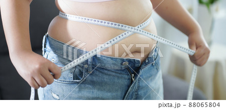 Obese Woman with fat belly in dieting concept. Overweight woman touching his fat belly and want to lose weight. Fat woman her waist with a centimeter..Shape up healthy stomach muscle and diet 88065804
