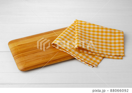 Wooden cutting board on cotton napkin on white wooden table 88066092