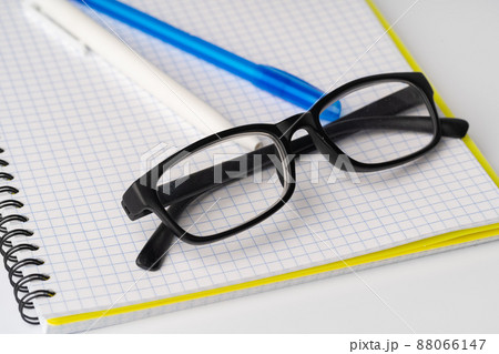 Two pens and glasses on open notepad, close up Two pens and glasses on open notepad, close up 88066147
