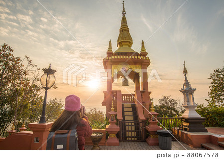 Tourist woman looking to the beautiful sunrise over Wat Phra That Doi Phra Chan one of the most beautiful Buddhist temple on the hills in Lampang province of Thailand. Tourist woman looking to the beautiful sunrise over Wat Phra That Doi Phra Chan one of the most beautiful Buddhist temple on the hills in Lampang province of Thailand. 88067578