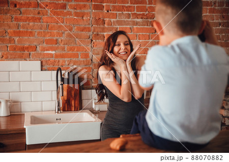 a beautiful pregnant mother plays with son in the kitchen. a happy family. a beautiful pregnant mother plays with son in the kitchen. a happy family. 88070882