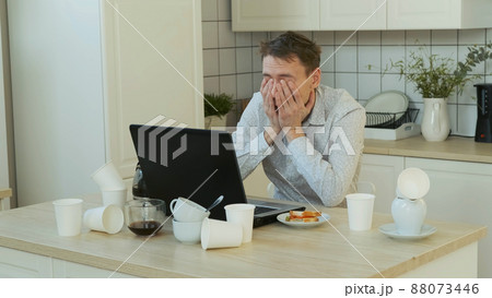 Exhausted Man Freelancer Overwhelmed with Job, Using Laptop All Night Long. Drinking from Coffee Pot. Working Overtime and Remote Work Concept 88073446