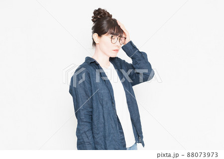 白い背景の前に立っている発熱で額に手を当てる眼鏡をかけている女性 白い背景の前に立っている発熱で額に手を当てる眼鏡をかけている女性 88073973