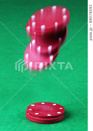 Red casino chips falling onto a card table with motion blur 88078092