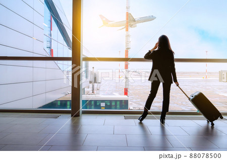 Girl at the airport window waits for a flight 88078500