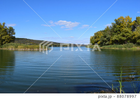 Beautiful lake, Calm blue water, big green trees, blue sky. Sunny day in autumn. Beautiful lake, Calm blue water, big green trees, blue sky. Sunny day in autumn. 88078997