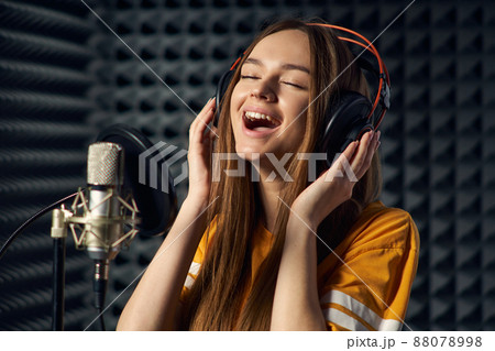 Teen girl in recording studio with mic over acoustic absorber panel background Teen girl in recording studio with mic over acoustic absorber panel background 88078998