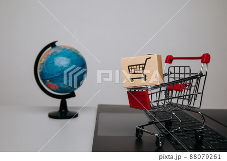 Paper box in a trolley on a keyboard and globe. Concept of online shopping Paper box in a trolley on a keyboard and globe. Concept of online shopping 88079261