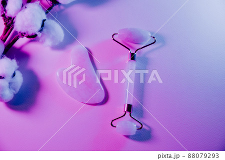 Skin care concept. Jade face roller for beauty facial massage therapy with fern leaf in neon light 88079293