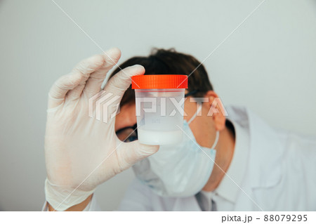 The doctor looks at the plastic jar with sperm for semen analysis. Medacine, Pills, medicine, vitamins concept The doctor looks at the plastic jar with sperm for semen analysis. Medacine, Pills, medicine, vitamins concept 88079295