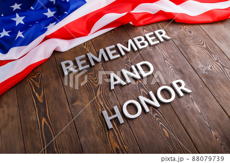words remember and honor laid with silver metal letters on wooden background with USA flag above 88079739