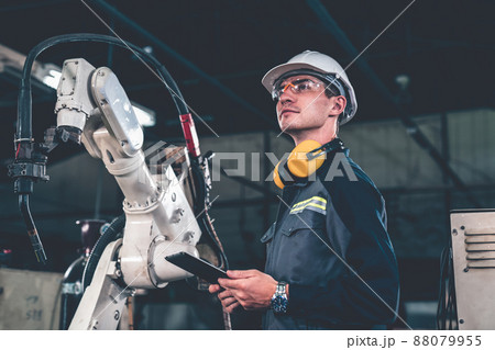 Young factory worker working with adept robotic arm Young factory worker working with adept robotic arm 88079955