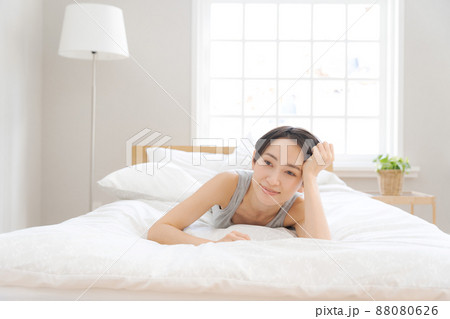 布団に寝転んで微笑む女性 布団に寝転んで微笑む女性 88080626