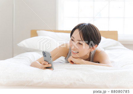 ベッドに寝転ぶ女性 スマホ ベッドに寝転ぶ女性 スマホ 88080785