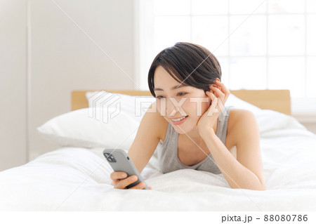 ベッドに寝転ぶ女性 スマホ ベッドに寝転ぶ女性 スマホ 88080786