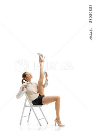 Portrait of young pretty girl, office worker in stylish cloth sitting, having online video call isolated over white studio background. Twine 88080882