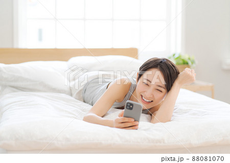 ベッドに寝転ぶ女性 スマホ ベッドに寝転ぶ女性 スマホ 88081070