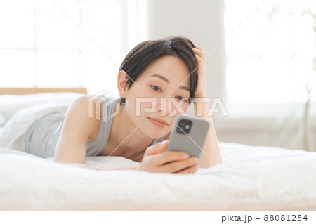 ベッドに寝転ぶ女性 スマホ 88081254