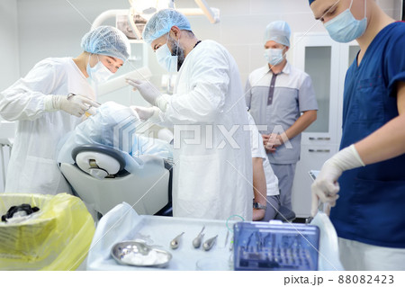 Surgeon and nurse during a dental operation.Anesthetized patient in the operating room.Installation of dental implants or tooth extraction in the clinic. Orthodontic surgery. Surgeon and nurse during a dental operation.Anesthetized patient in the operating room.Installation of dental implants or tooth extraction in the clinic. Orthodontic surgery. 88082423