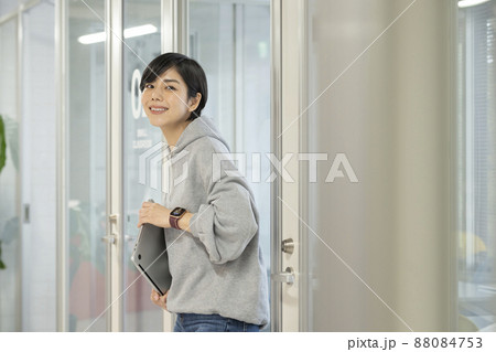 ノートパソコンを持ったカメラ目線で笑顔の若い女性　カジュアルビジネス　イメージ 88084753