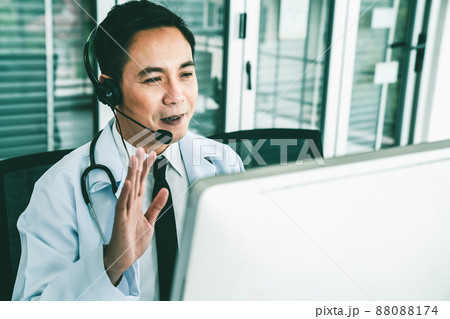 Doctor wearing headset talking actively on video call in a clinic or hospital . Doctor wearing headset talking actively on video call in a clinic or hospital . 88088174