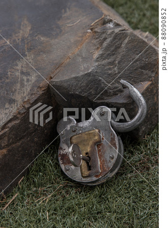 Old vintage iron padlock front of Huge stone on grass background. Old vintage iron padlock front of Huge stone on grass background. 88090852