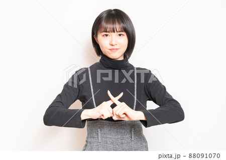 白い背景の前に立ってNGのポーズをする若い女の子 88091070