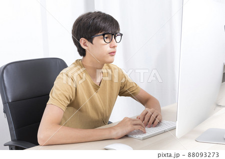 Handsome white boy with eyeglasses study online via computer on table at home. Handsome white boy with eyeglasses study online via computer on table at home. 88093273