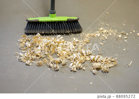 a small pile of wood shavings on a gray linoleum floor with a broom brush a small pile of wood shavings on a gray linoleum floor with a broom brush 88095272