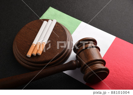 Cigarettes, wooden Judge gavel and flag of Italia. Tobacco law. Legal responsibility for the sale and purchase of cigarettes. Smoking in Italy. Cigarettes, wooden Judge gavel and flag of Italia. Tobacco law. Legal responsibility for the sale and purchase of cigarettes. Smoking in Italy. 88101004