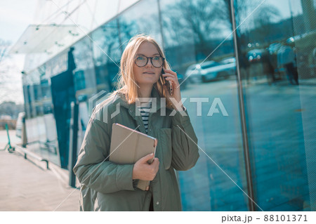 Smiling young girl in casual clothes using mobile phone 88101371