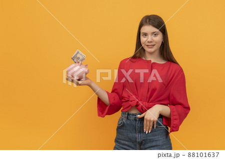 Young woman or teenage girl holds piggy bank with money in hands. Financial planning, savings. Financial literacy concept Young woman or teenage girl holds piggy bank with money in hands. Financial planning, savings. Financial literacy concept 88101637
