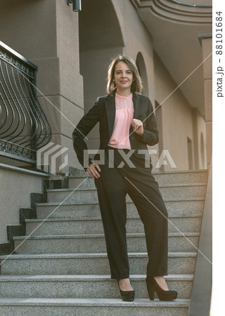 Attractive woman in business clothing on the stairs. Woman wearing black suit. Young stylish woman 88101684