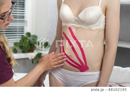 Young woman with ribbons on her stomach. Estetic taping. Kinesiology tapes. Tummy tuck. Young woman with ribbons on her stomach. Estetic taping. Kinesiology tapes. Tummy tuck. 88102195