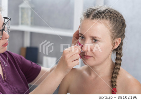 Cosmetologist sticks tapes on the girls face. Facelift. Tape for facelift with kinezio. Aesthetic patch for face. Cosmetologist sticks tapes on the girls face. Facelift. Tape for facelift with kinezio. Aesthetic patch for face. 88102196