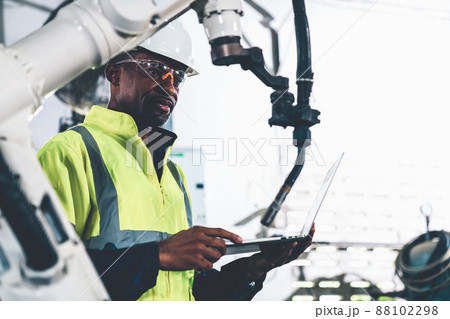 African American factory worker working with adept robotic arm African American factory worker working with adept robotic arm 88102298