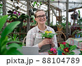 Young woman sells flowers and seedlings via video link on laptop via the Internet. Gardening, sales 88104789