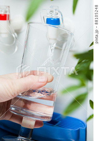 hand pouring a glass of water from dispenser 88105248