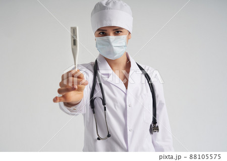 Young female doctor showing thermometer over white background, studio shot Young female doctor showing thermometer over white background, studio shot 88105575