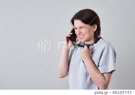 Woman talking on chained mobile phone over grey background, addiction concept 88105745