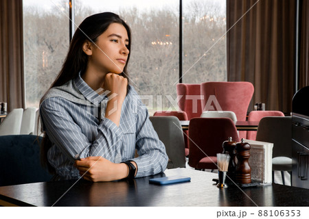Sad beautiful young woman with smartphone waiting for boyfriend in restaurant Sad beautiful young woman with smartphone waiting for boyfriend in restaurant 88106353