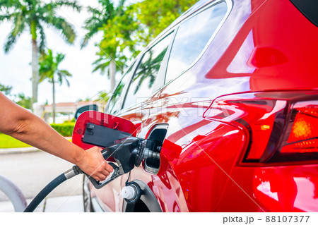 Female Hand with fuel pistol and red car 88107377