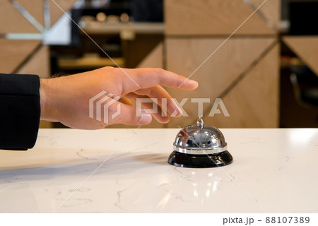 Hand of a man is going to use a vintage hotel bell Hand of a man is going to use a vintage hotel bell 88107389